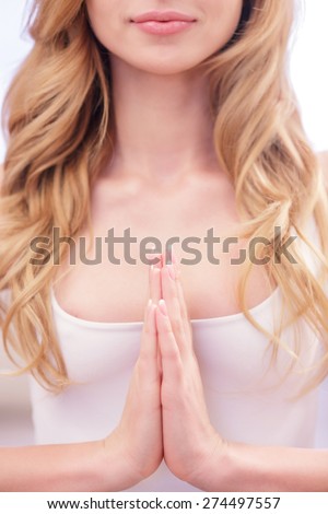 Creating Namaste. Youthful blond woman putting her palms together on her chest area.