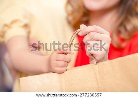 Hands of a small girl and a woman holding a package in a boutique close up selective focus