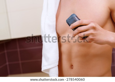 Holding fast. Close up of topless man with towel on his shoulder holding electric razor