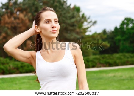 Stay positive. Young beautiful woman standing in park with hand behind her head