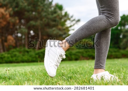 Showing off. Close-up portrait of pleasant slender woman legs standing on green grass