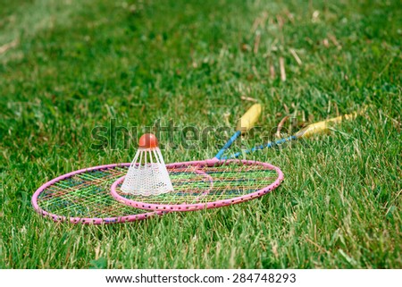 Active vacation. Picture of two badminton racquets lying on the green grass and a shuttlecock on them