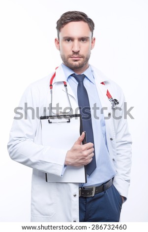 Overwhelming seriousness. Serious doctor holding  papers and keeping the hand in his pocket while standing isolated on white background