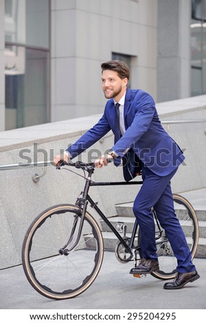 Ready, steady, go. Nice  handsome bearded businessman holding bicycle and smiling while going to ride.