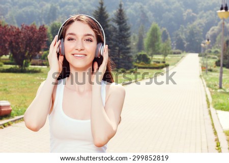 Listen to my favorite song. Smiling beautiful girl wearing headphones and holding them while listening to music.