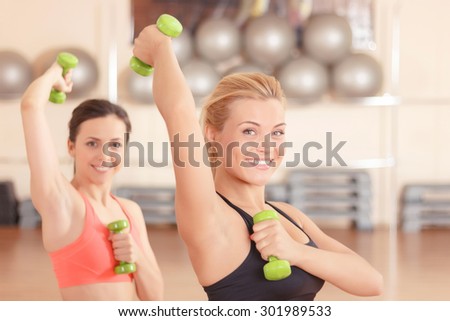 Lets move. Portrait of young strong women doing fitness exercises by using little dumbbells.