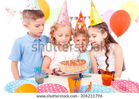 So tasty. Group of little cute smiling children curiously looking at cake during birthday party