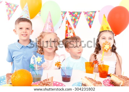 Flowers to girls. Two little cute boys and pair of pretty girls with toy flowers during birthday party.