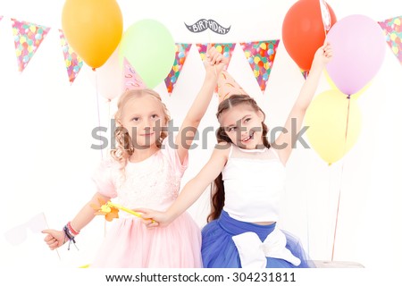 Little princesses. Two beautiful little girls happily dancing during birthday party.