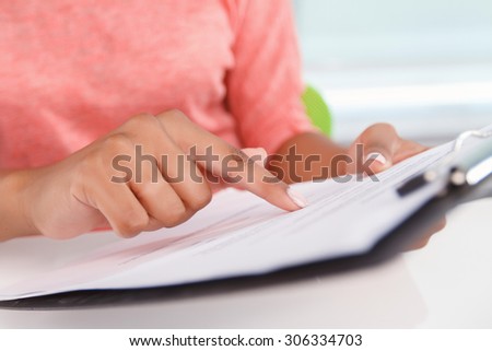 Careful work. Close p portrait of woman holding folder with papers and pointing on them with her index finger