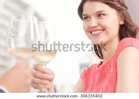 Celebrating anniversary. Close up portrait of young attractive smiling lady clinking glasses with her boyfriend