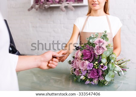 Good choice. Close up of credit card in hands of professional florist while getting it from client and doing her job