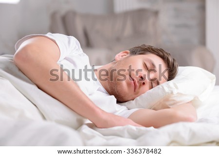 Fast sleep. Good-looking young guy sleeps innocently in his bed before working day officially begins.