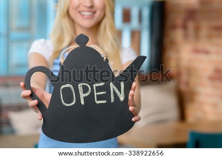 We are open. Selective focus of notice in hands of cheerful content welcoming waitress waiting for clients