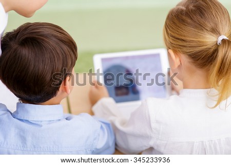 Digital work. Group of tree children is absorbed in new digital tablet.