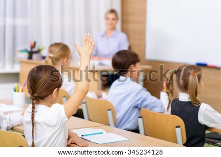 Nice pupils. Little pupil is raising her hand in the air indicating that she knows the answer to teachers question.