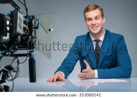 Newsreader in action. Handsome newsman is busy reporting news on the camera.