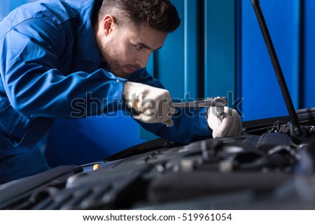 Concentrated mechanic repairing car engine