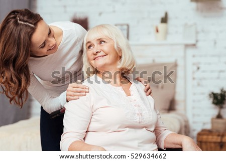 Cheerful woman taking care of her grandmother in wheelchair