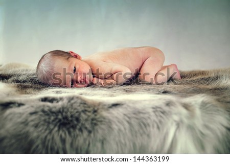 one week baby laying on animal skin