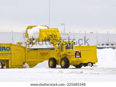 JFK Airport January 2011 Wheel loader machine unloading snow to snow melter with airport work crews after large storm at JFK Airport on January 13, 2011 clearing off taxi ways and run ways.