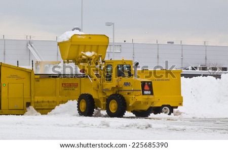 JFK Airport January 2011 Wheel loader machine unloading snow to snow melter with airport work crews after large storm at JFK Airport on January 13, 2011 clearing off taxi ways and run ways.
