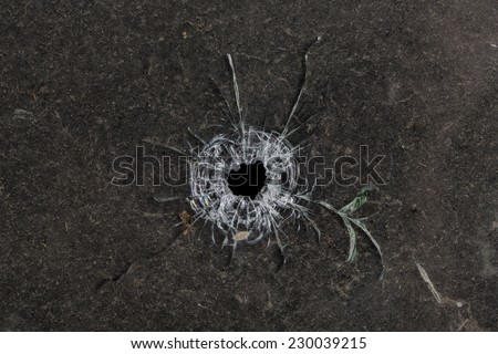 Bullet hole in glass on dirty grungy black background