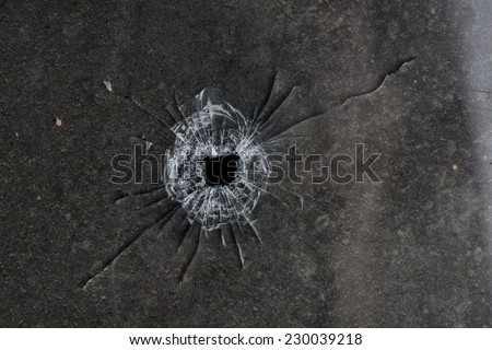 Bullet hole in glass on dirty grungy black background