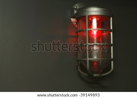 Red light bulb glowing from  fixture in dark room