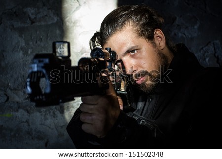 Young soldier holding gun, dressed in black, underground. Special Forces