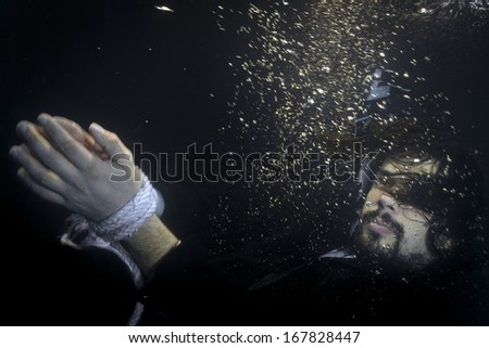 Businessman having his hands tight with rope thrown in the river, sinking,underwater shot.
