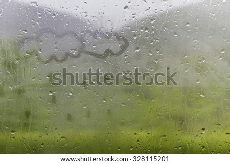 Clowds drawn on the foggy glass window on a raining day