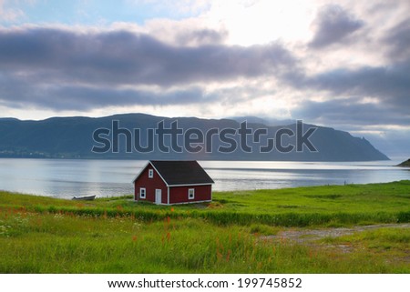 Red wooden cabin on the shore in Nordic landscape