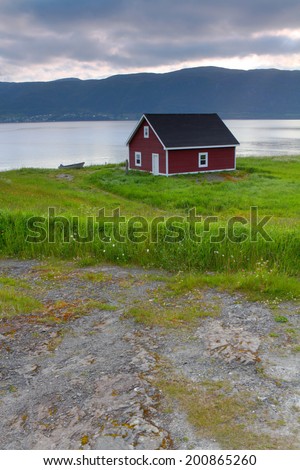 Red wooden cabin on the shore in Nordic landscape