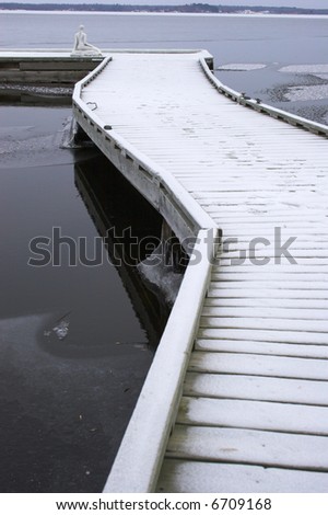 Lonely winter pier over partially frozen lake