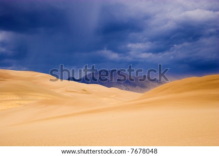 Thunder clouds, rain and sand are being blown over great sanddunes