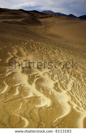 Thunder clouds, rain and sand are being blown over great sanddunes