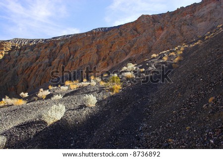 Fragment of black lava and orange clay and salt mineral deposits in geological formations in Ubehebe Volcano, Death Valley National Park