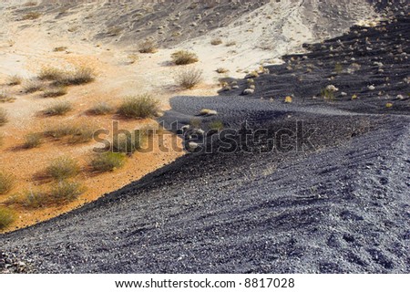 Fragment of black lava and orange clay and salt mineral deposits in geological formations in Ubehebe Volcano, Death Valley National Park