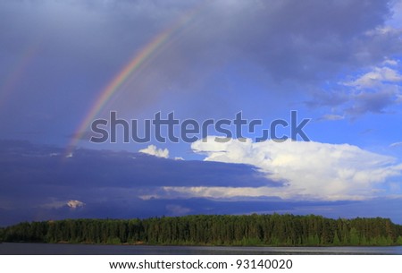 Rainbow breaks through storm clouds after the rain over lake in Minnesota, USA