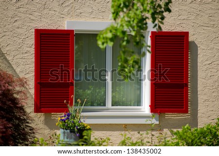 open sun blind of red color and house window in a sunny day, Switzerland