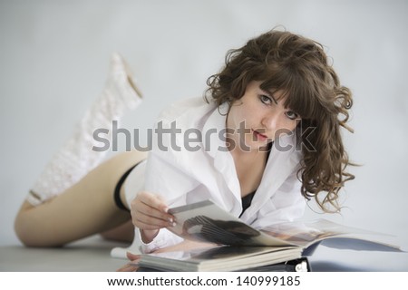 beautiful woman with a flowing hair in a shirt and linen looks the book