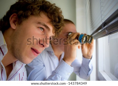 couple of detectives observe through a window by means of the field-glass