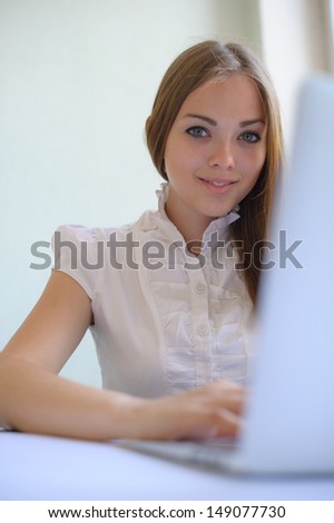 portrait of the attractive business woman working with the laptop on a light background