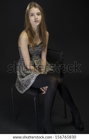 portrait of a beautiful young woman with her hair sitting on a chair on a black background