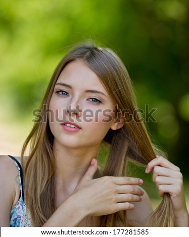 Girl looks. Portrait of a girl in a park. Woman with her hair. Girl straightens hair.