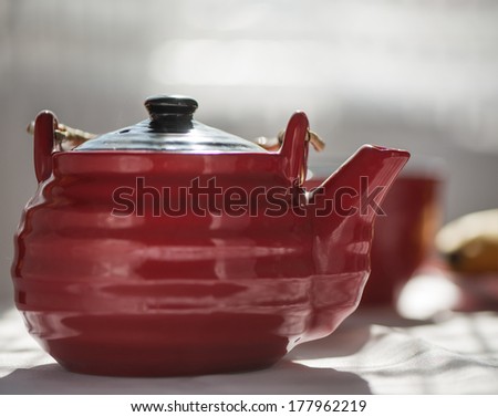 Red Kettle. Tea Party. Teapot for tea on a background of the dishes on the table.