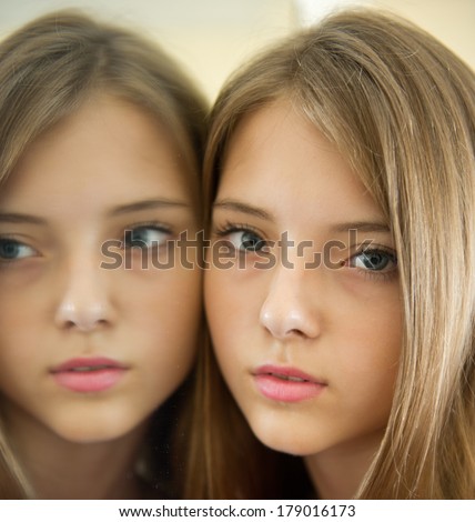 Portrait of a beautiful young girl at the mirror. Cute girl standing pressed against his clinging to the mirror image.