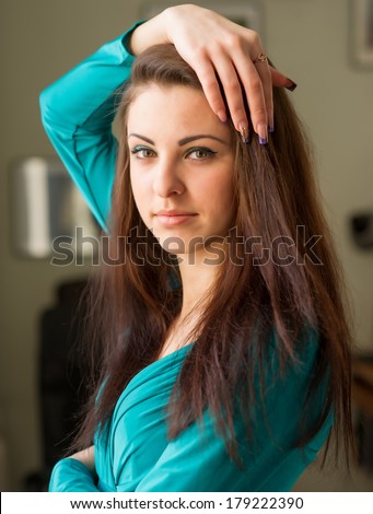 Beautiful young woman with long hair. Cute girl looks into the camera and straightens hair