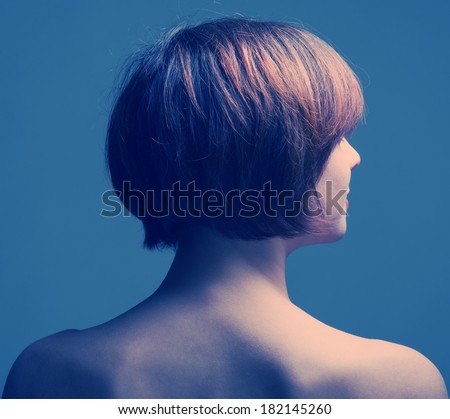 Head of a woman with short hair from the back on a dark background.
